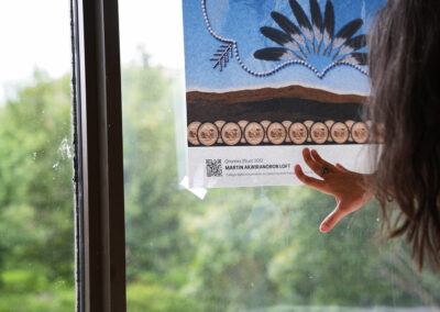 Une médiatrice culturelle accroche une œuvre sur une fenêtre