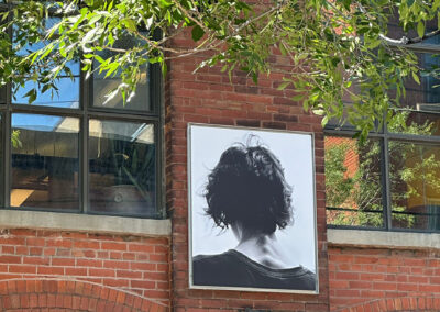 Portrait d'une femme de dos en noir et blanc exposé sur une façade en briques