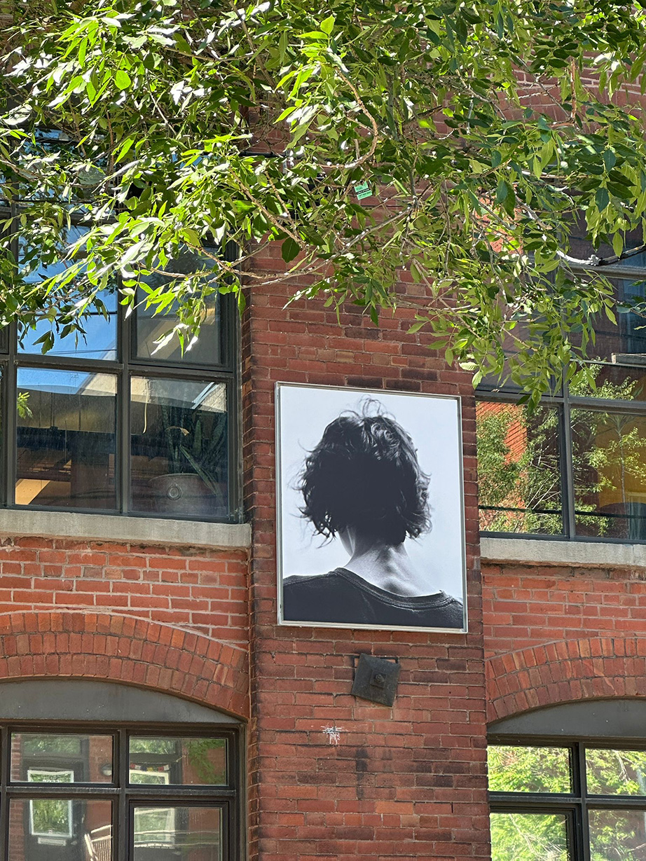 Portrait d'une femme de dos en noir et blanc exposé sur une façade en briques